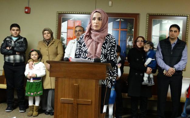 With three Syrian refugee families standing behind her, Nora Basha, with the Syrian American Council of Indiana, speaks during a press conference before a Dec. 11 rally and candlelight vigil in support of Syrian refugee families. The event was held by the council at Epworth UMC in Indianapolis. Dan Gangler photo, UMNS